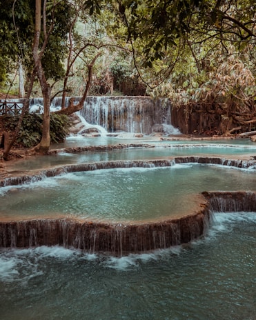 A cascading waterfall with crystal clear water inviting visitors to relax nearby.