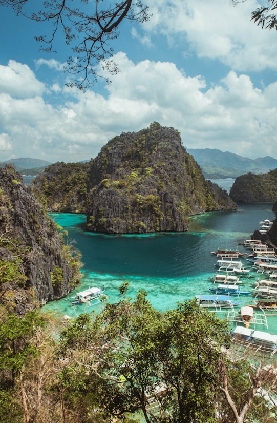 green and brown mountain beside body of water under blue sky during daytime