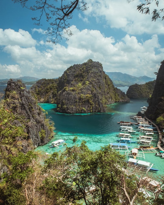 green and brown mountain beside body of water under blue sky during daytime in Coron Island Philippines