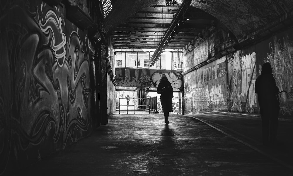 grayscale photo of person walking on hallway