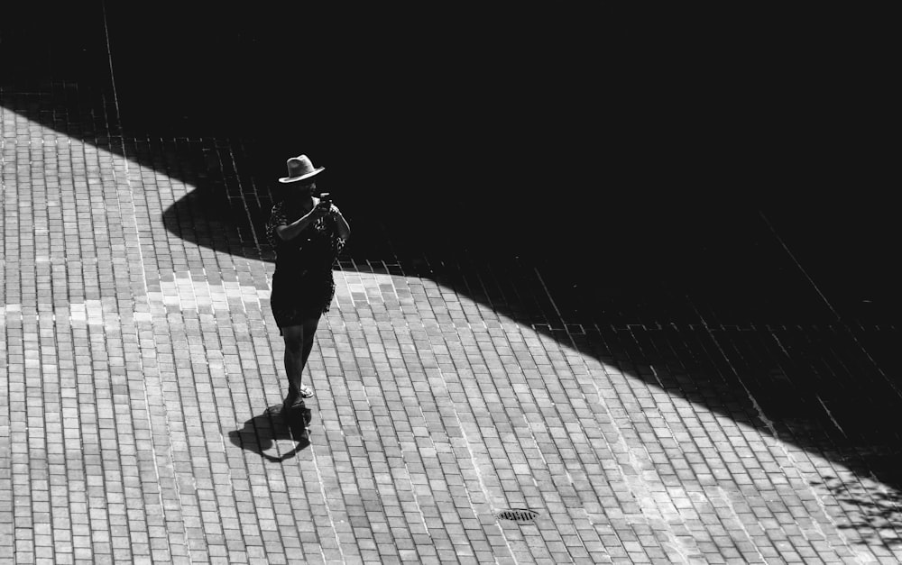 grayscale photo of person walking on sidewalk