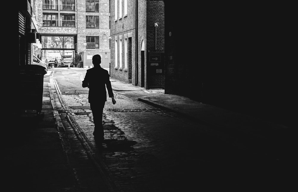 grayscale photo of person walking on street