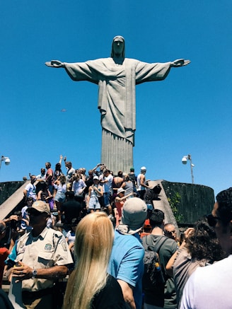 people gathering in a park with statue of liberty in the distance, Christ The Redeemer, Rio de Janei