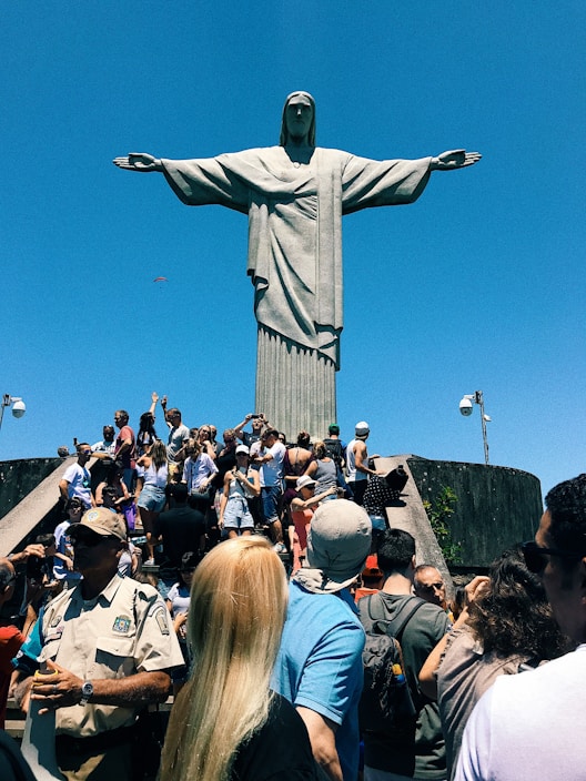 people gathering in a park with statue of liberty in the distance, Christ The Redeemer, Rio de Janei