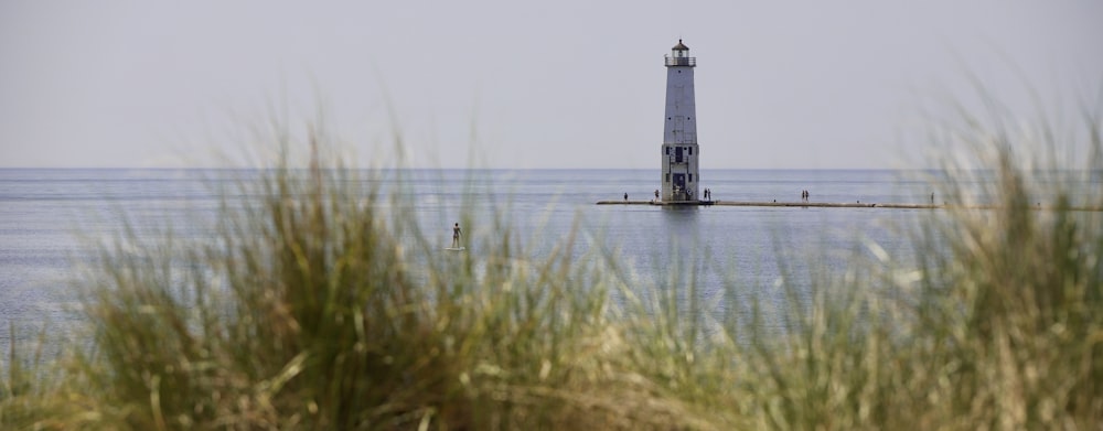 white and black lighthouse on body of water during daytime