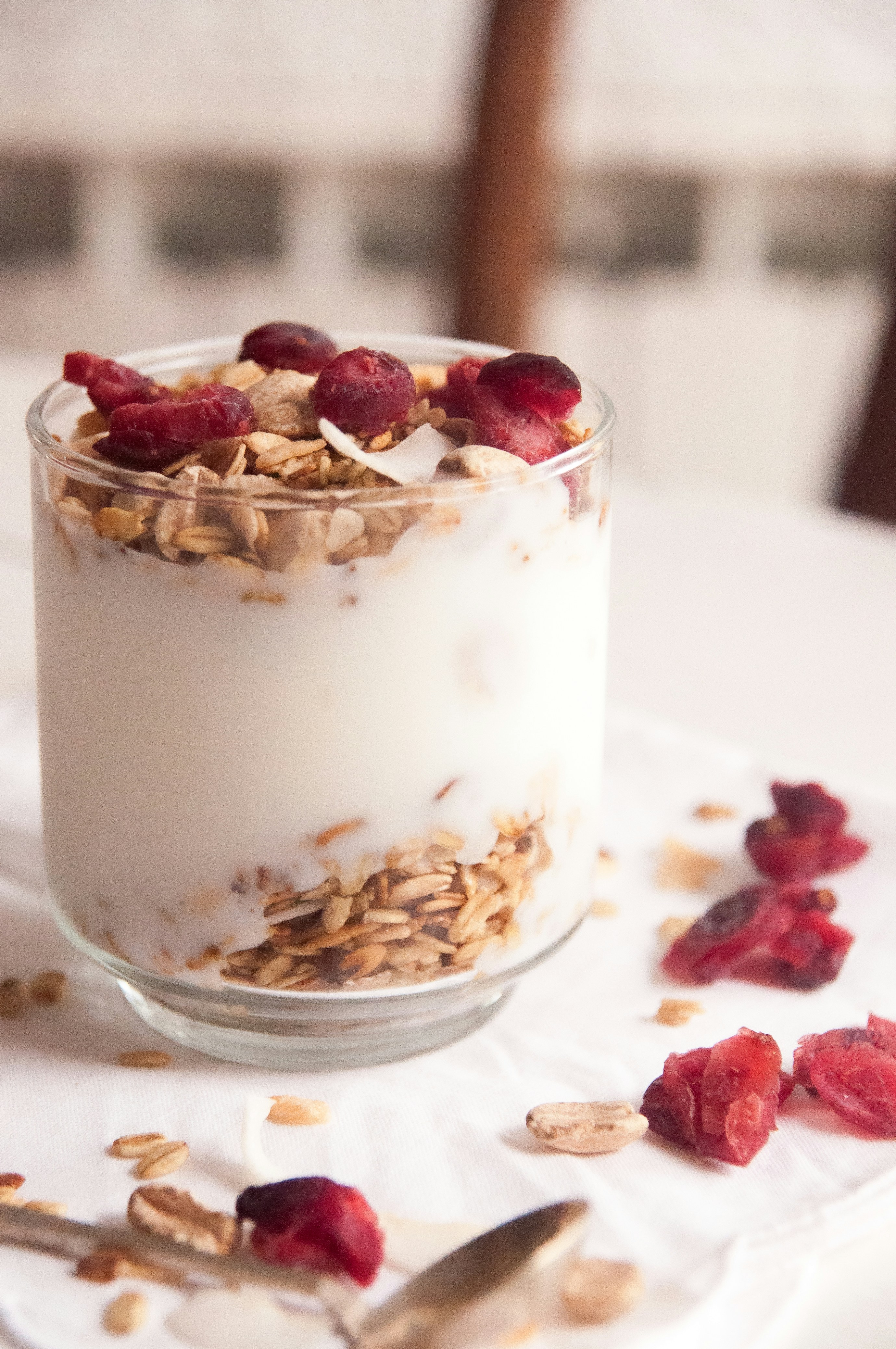 A cup of creamy Greek yogurt topped with fresh mixed berries and a small sprinkle of crunchy granola