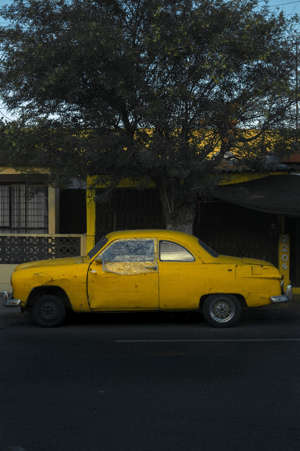 yellow sedan parked near brown tree