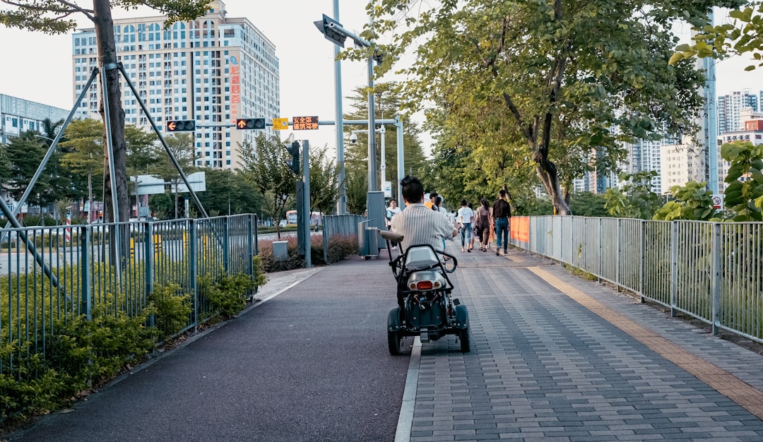 people riding on green and black golf cart on gray concrete road during daytime