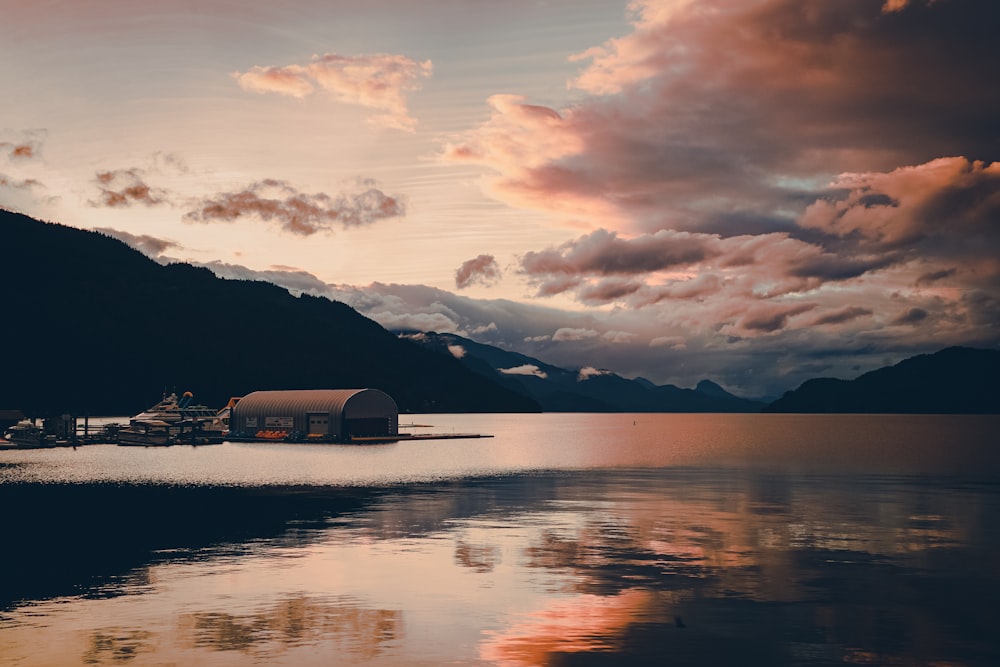 body of water near mountain under cloudy sky during daytime