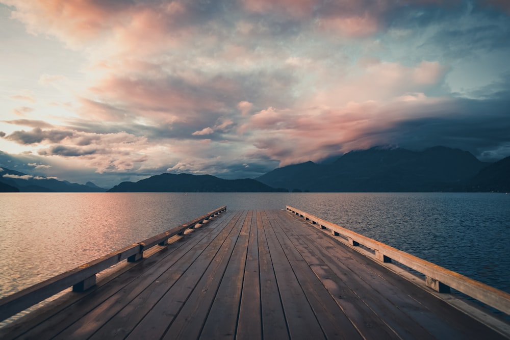 brown wooden dock on sea under cloudy sky during daytime