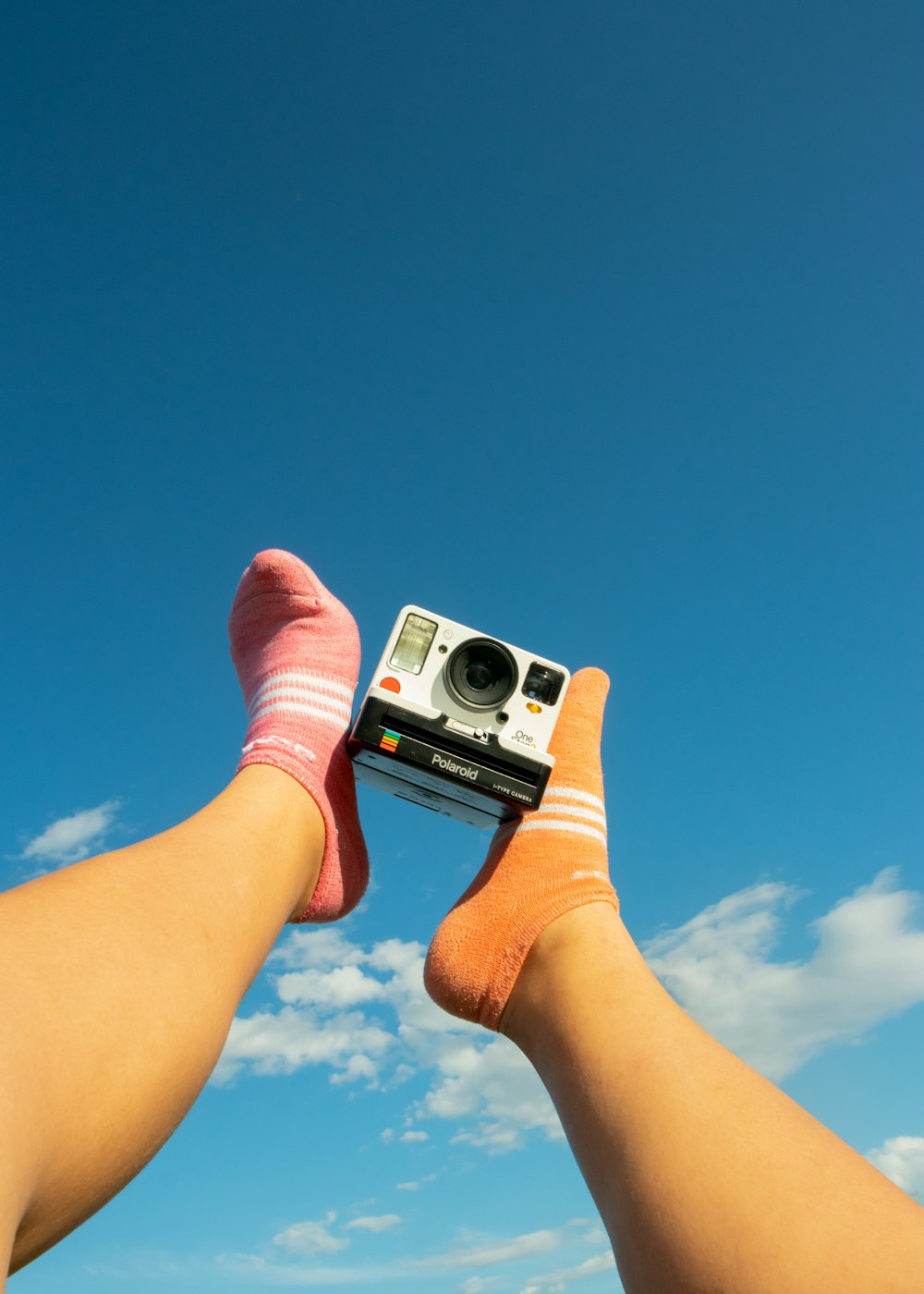 person holding white and black camera under blue sky during daytime