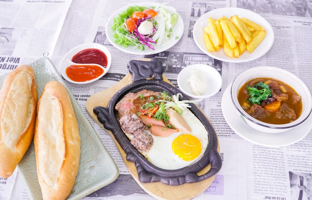 a table topped with plates of food and bread