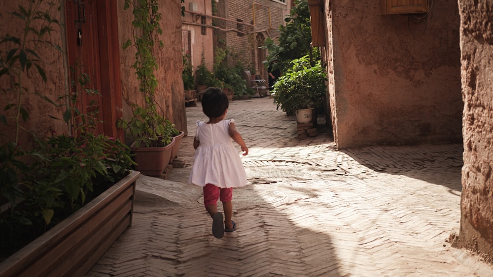 girl in white dress walking on sidewalk during daytime