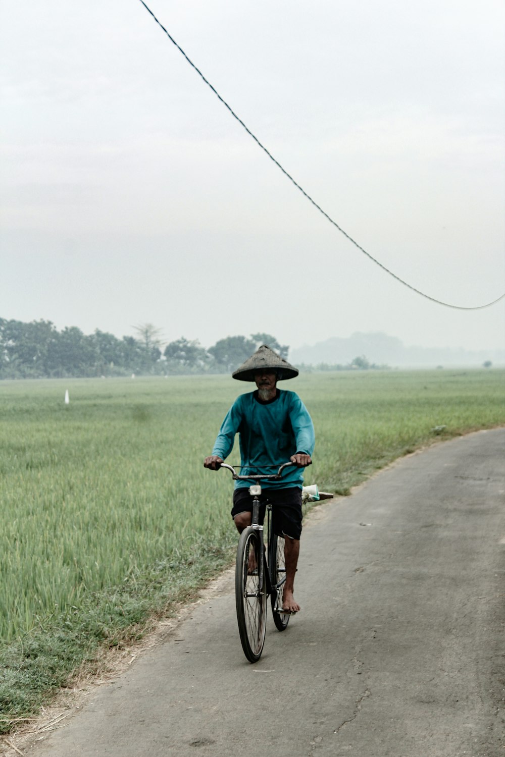 man in blue shirt riding bicycle on road during daytime