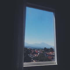 Window framing the peak of a distant mountain with clear blue skies overhead.