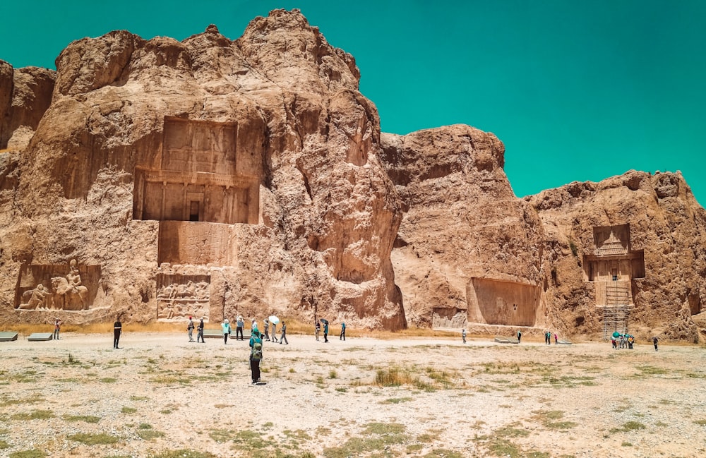 people walking on brown sand near brown rock formation during daytime