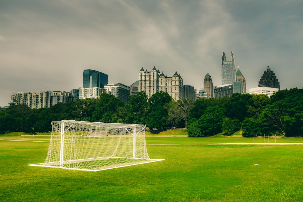 Red de portería de fútbol blanca en el campo de césped verde cerca de los edificios de la ciudad durante el día