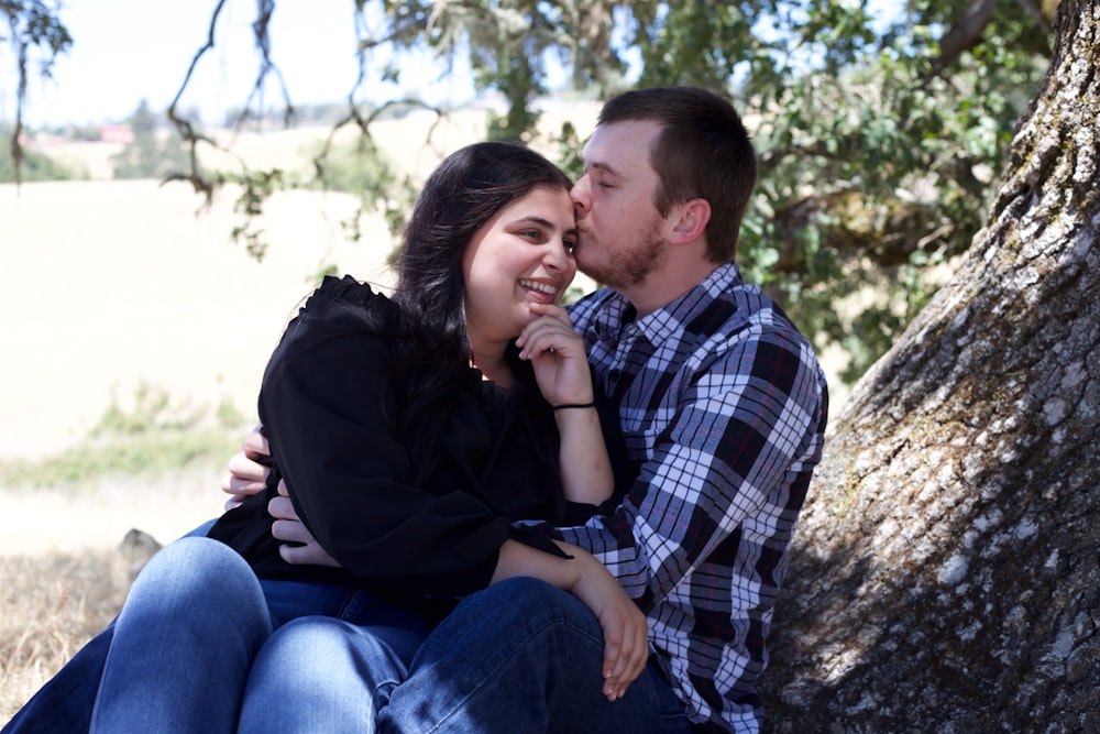 man and woman kissing near trees during daytime