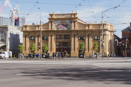 people walking on pedestrian lane near brown concrete building during daytime in Queen Victoria Market Australia