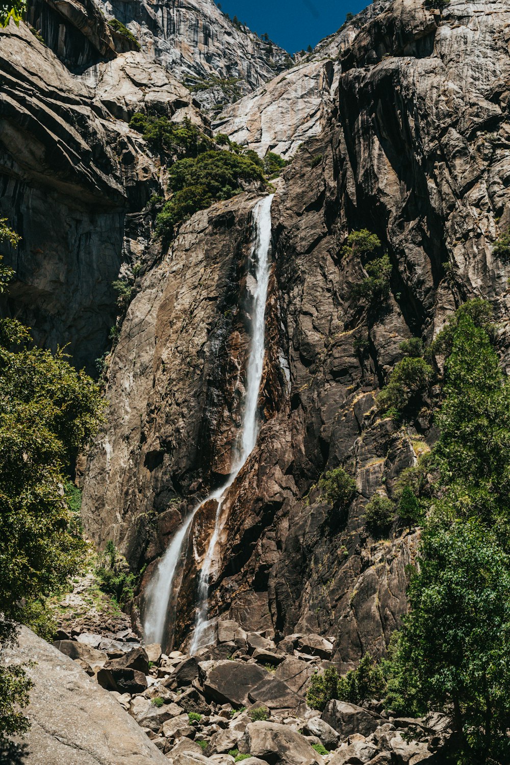 waterfalls in between green trees during daytime