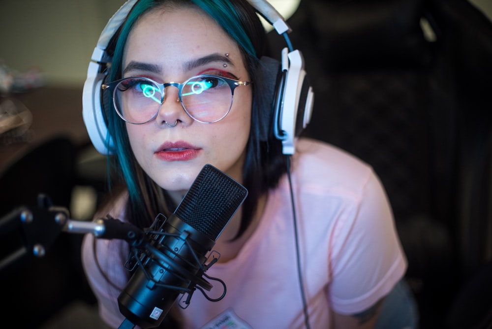 woman in white shirt wearing blue headphones holding black microphone