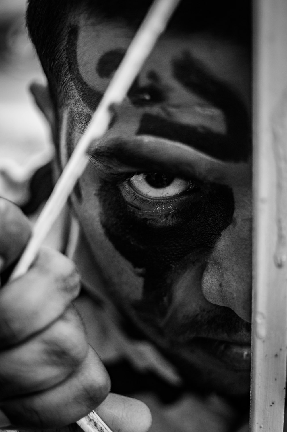 grayscale photo of man holding stick