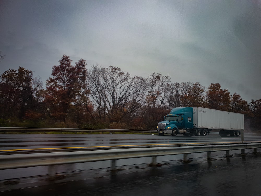 blue truck on road near bare trees during daytime