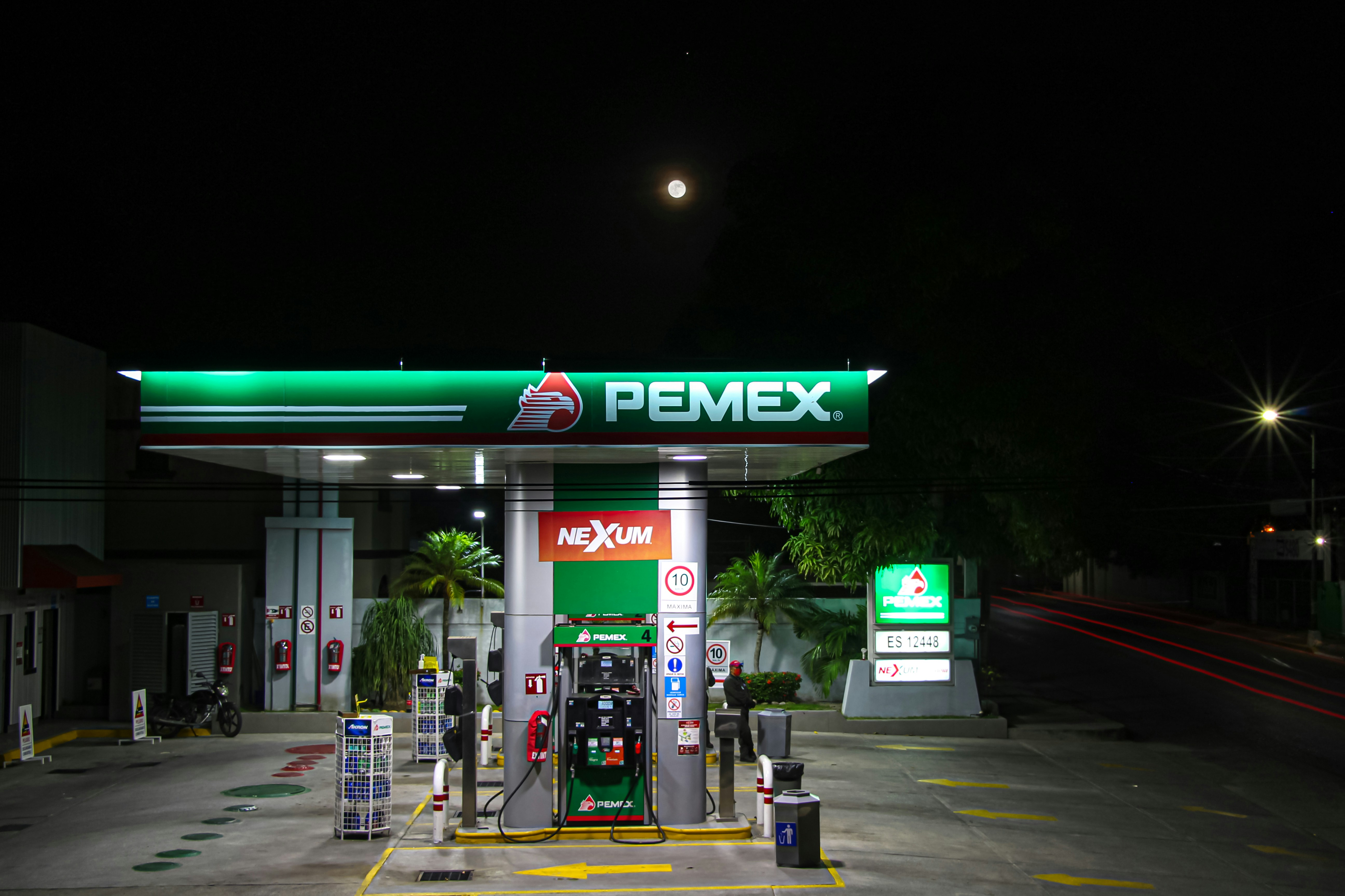 Gasolinera a media noche con la luna de fondo.
