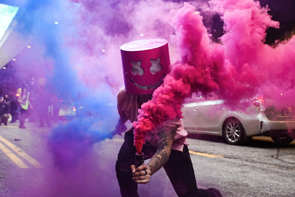 person in black jacket holding pink smoke