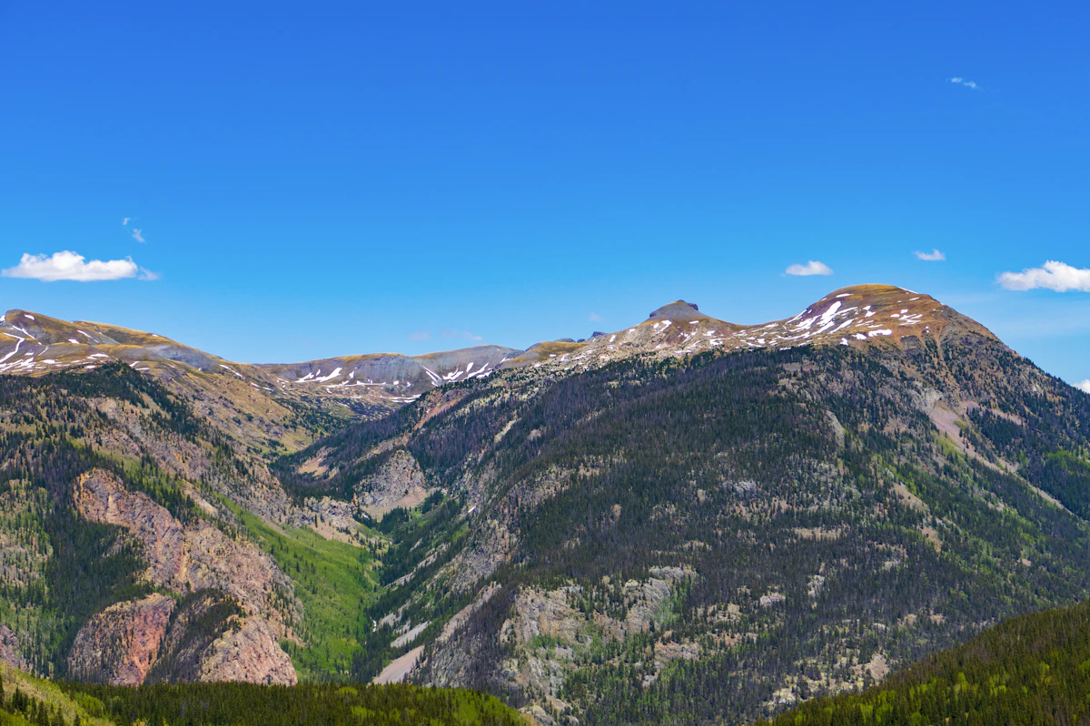 A rocky ridge with patches of snow above a forested canyon near Silverton