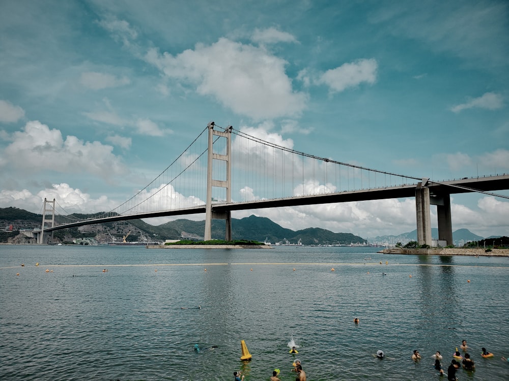 people riding on yellow kayak on sea near bridge under white clouds and blue sky during