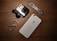 A collection of gadgets placed on a wooden surface including a GoPro camera, a smartphone with an Apple logo, a carabiner clip, and a multitool.