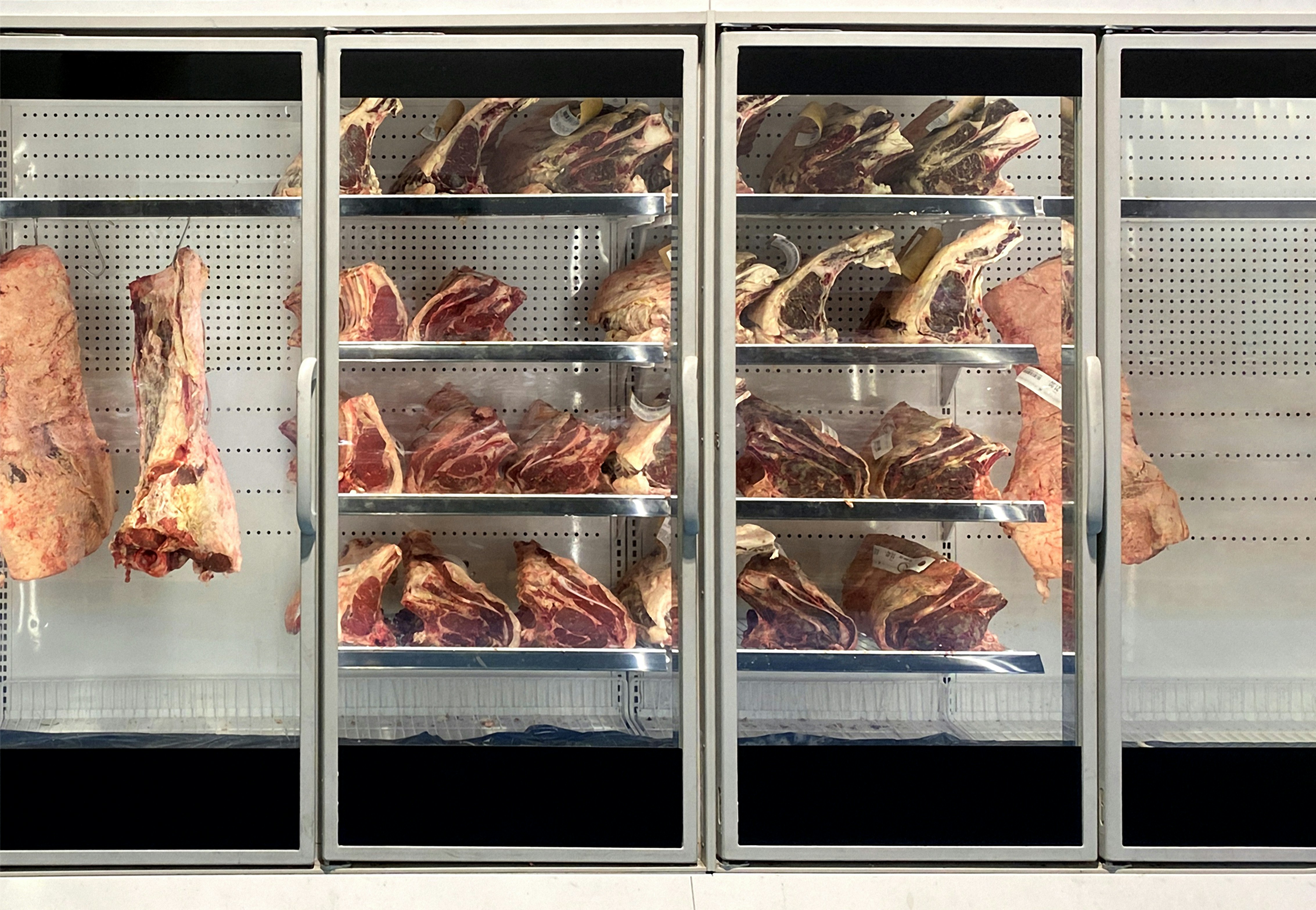 Premium fresh meat cuts displayed in a butcher case with clean presentation