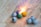 A collection of small spherical fireworks is arranged on a wooden surface. One of the fireworks is lit, emitting bright sparks and a burst of light. The spheres are in various colors, including gray, green, blue, and yellow, some with visible fuses.