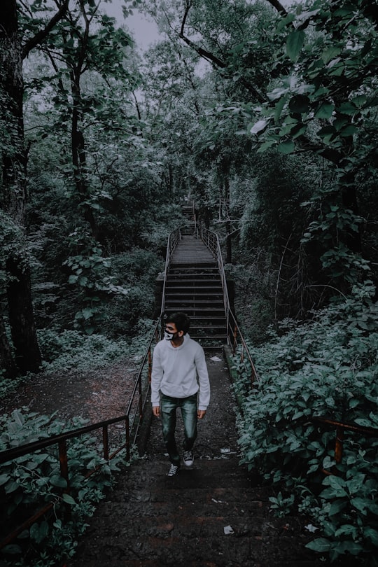 man in white shirt walking on wooden bridge in Nagpur India