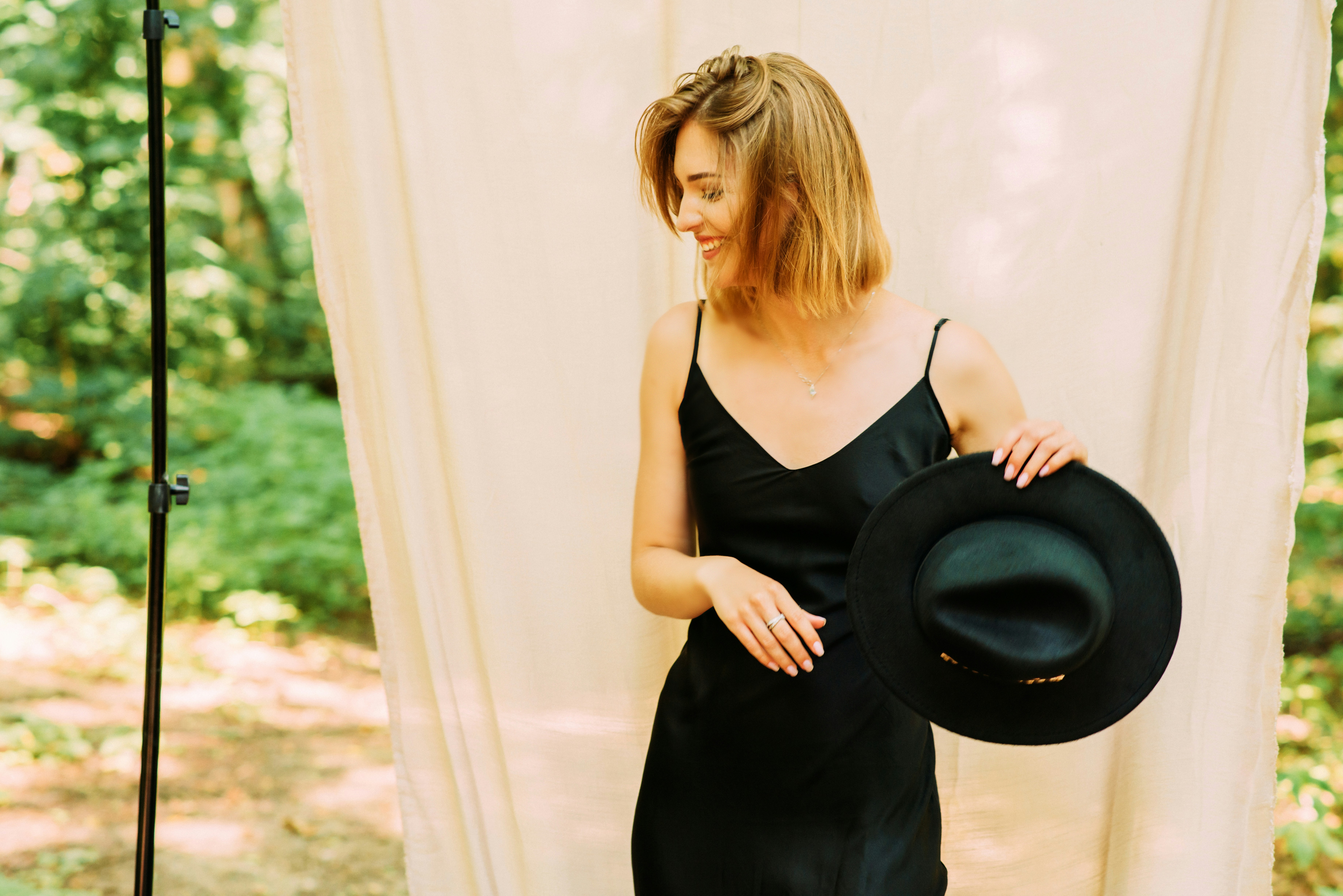 woman in black spaghetti strap dress holding black hat