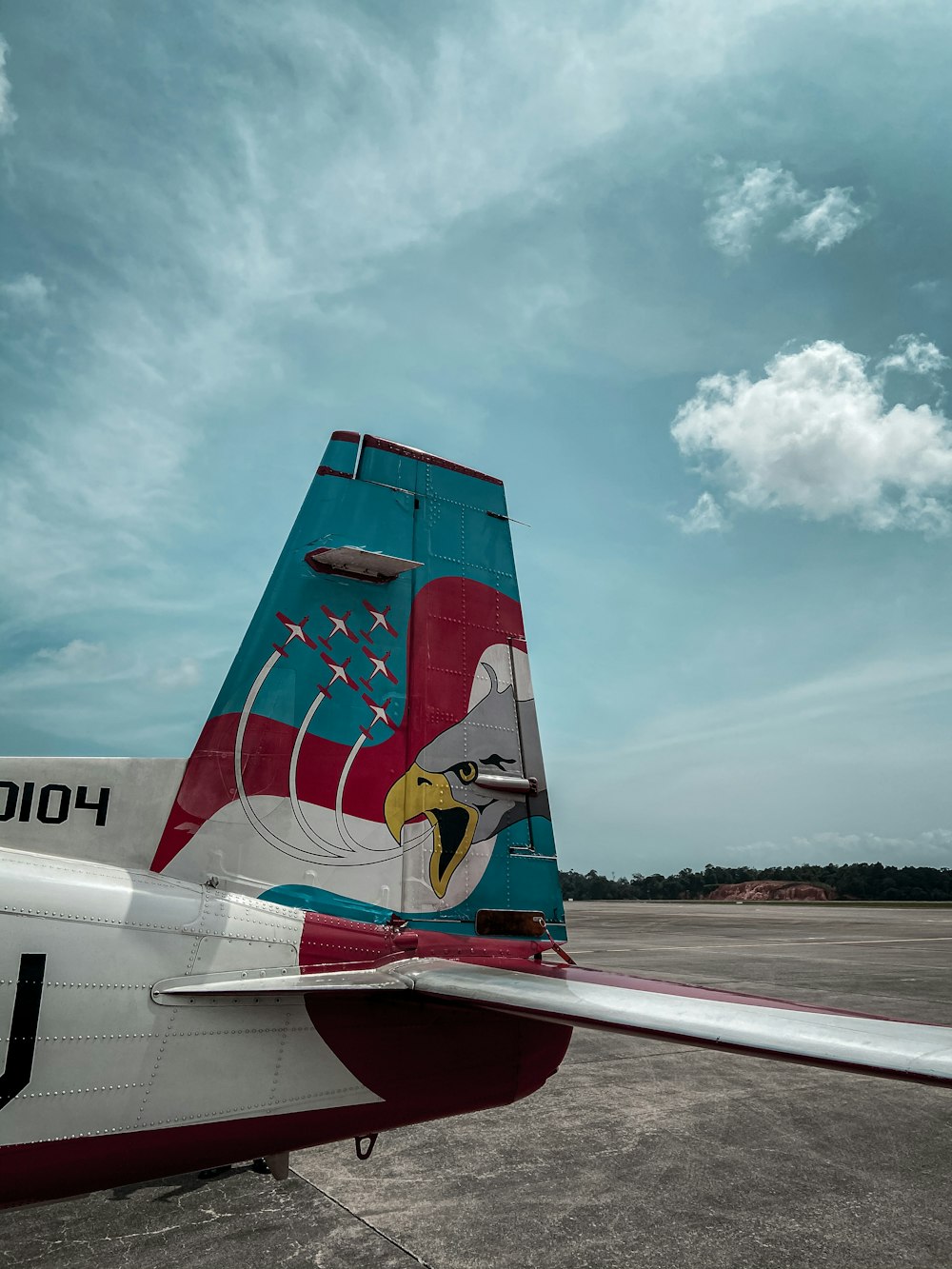 red and white airplane under white clouds and blue sky during daytime