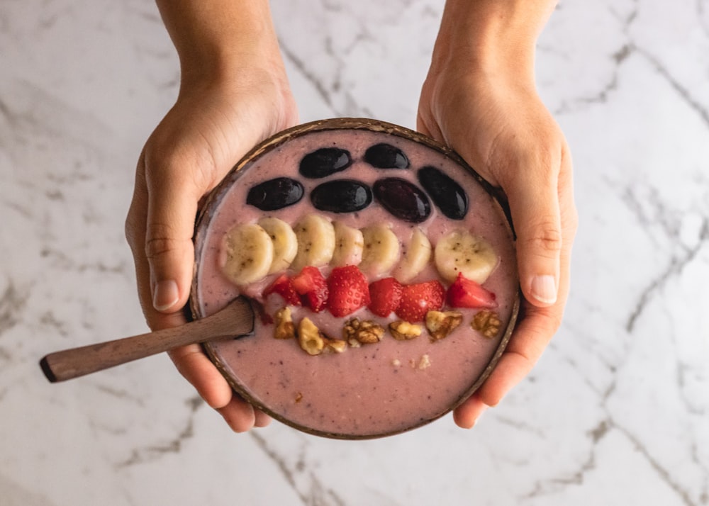 person holding brown round cake with strawberry on top