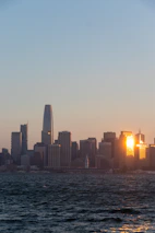 Downtown LA skyline at sunset with soft gold and blue tones reflecting in glass buildings.