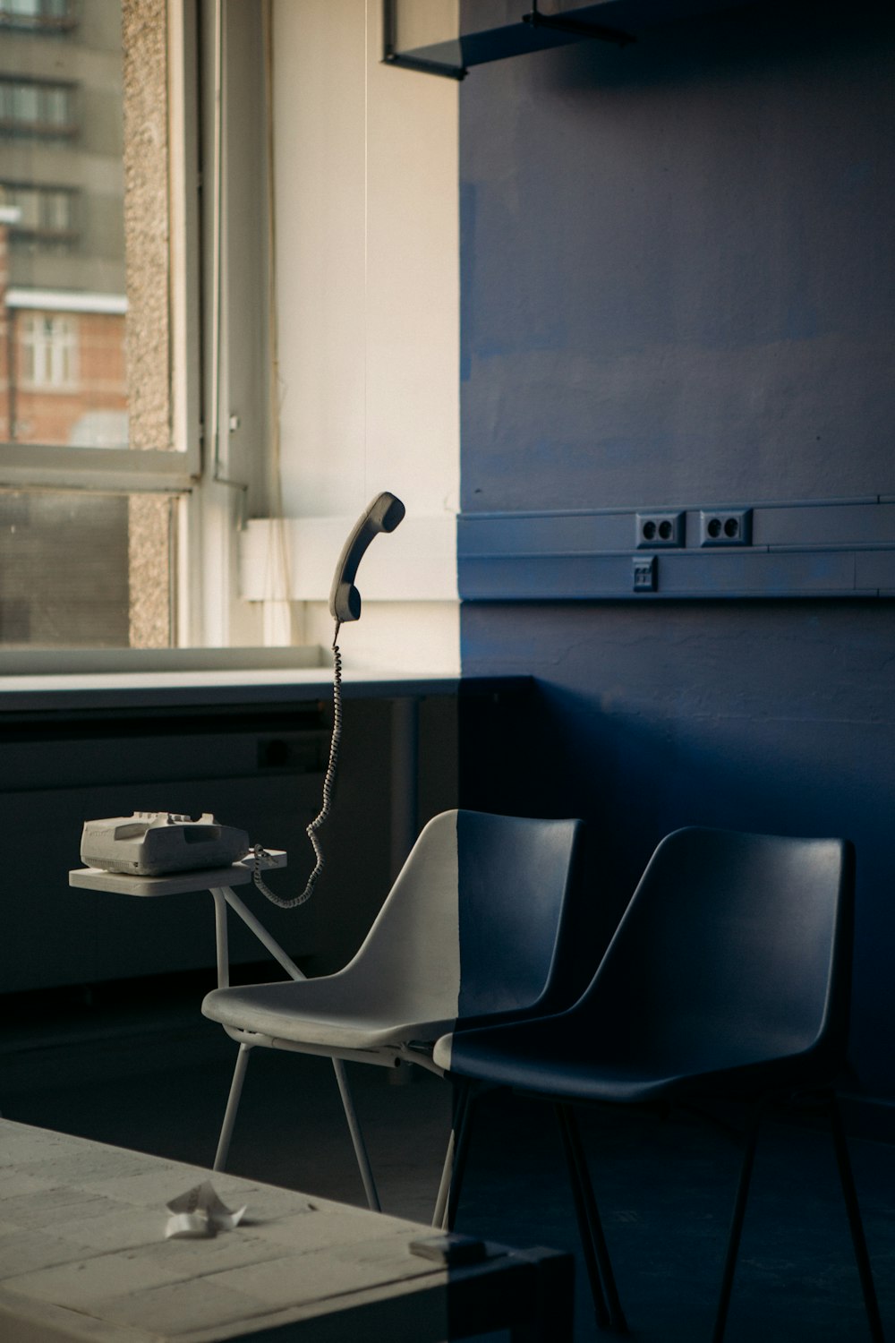 white and black chair beside blue wall