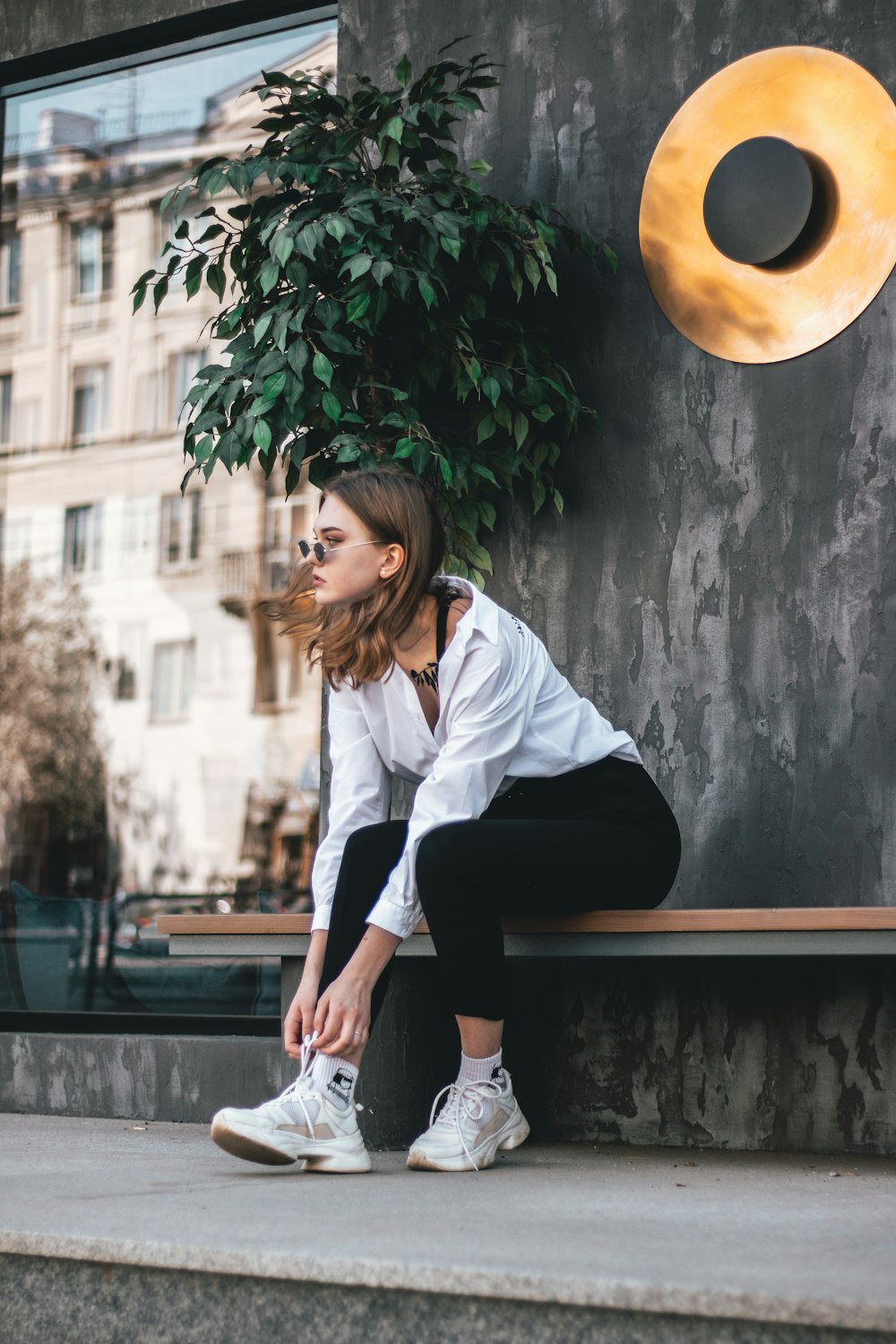 woman in white long sleeve shirt and black pants sitting on brown wooden bench