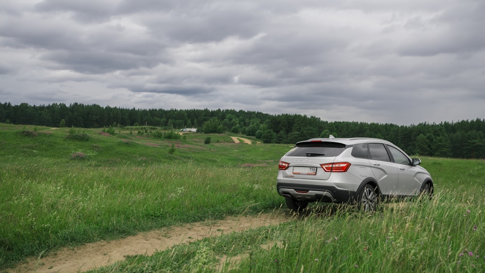 white suv on road near green grass field under white clouds during daytime