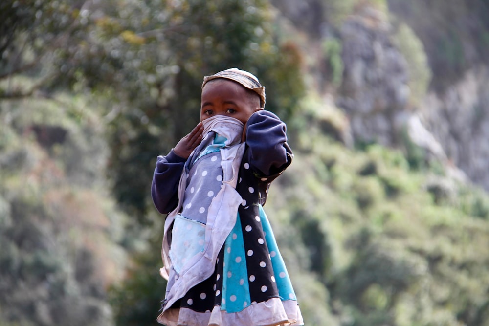 woman in black leather jacket carrying baby in white and blue polka dot dress