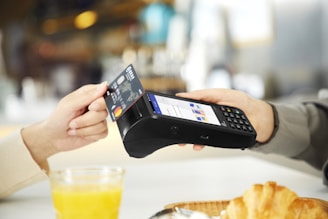 person holding black smartphone near clear drinking glass