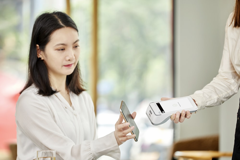 woman in white dress shirt holding silver iphone 6
