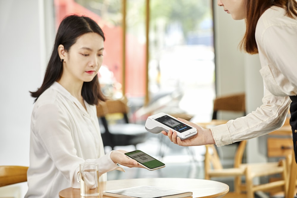 woman in white long sleeve shirt holding white smartphone