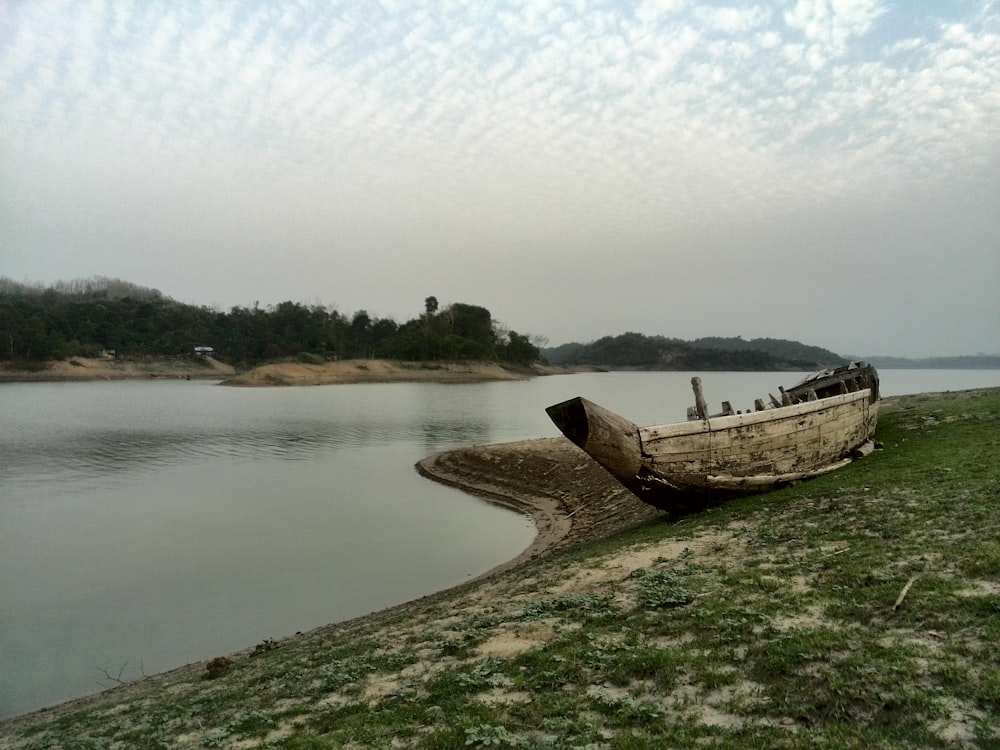a boat sitting on the shore of a lake
