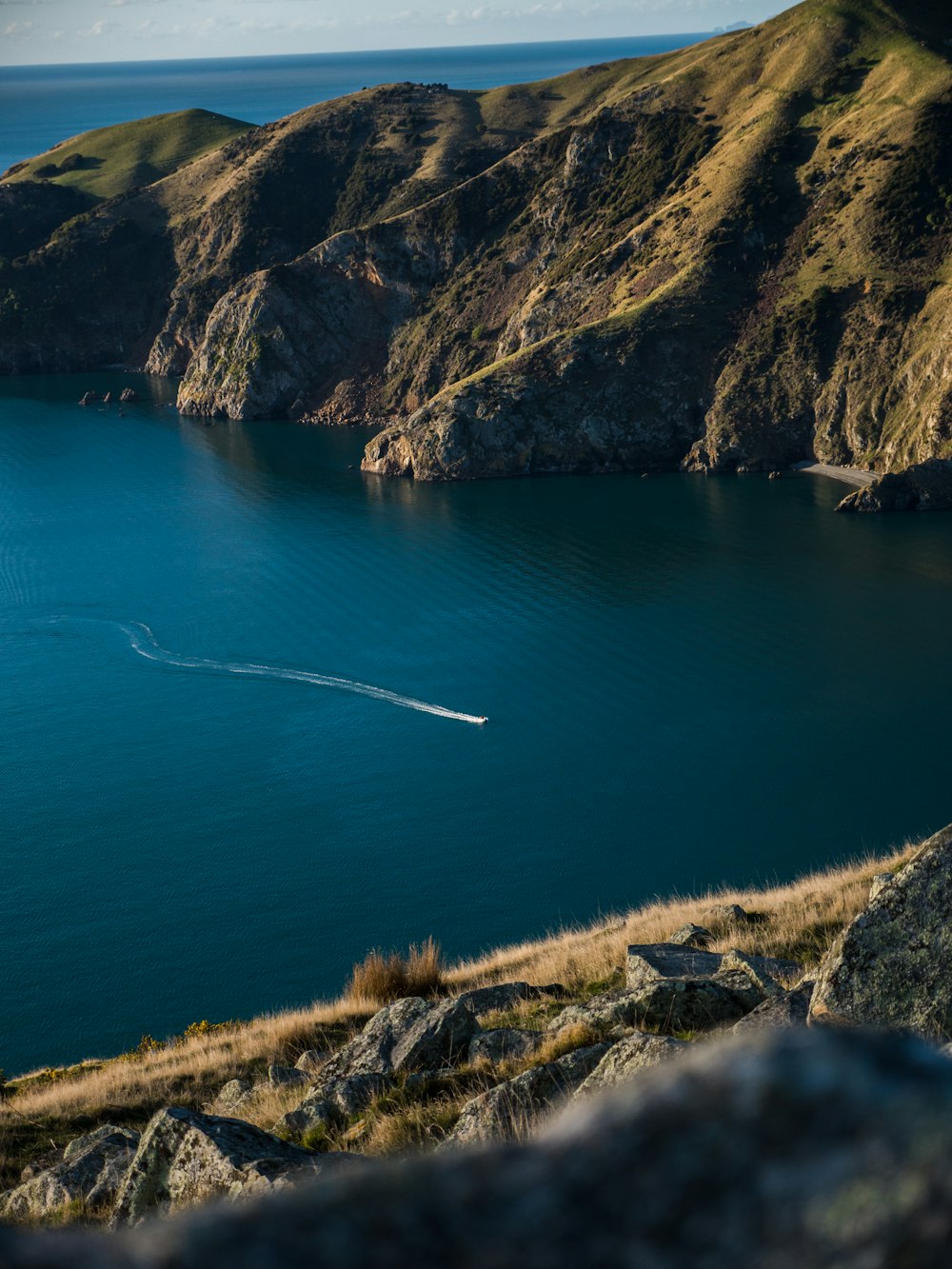 blue sea beside brown and green mountain during daytime