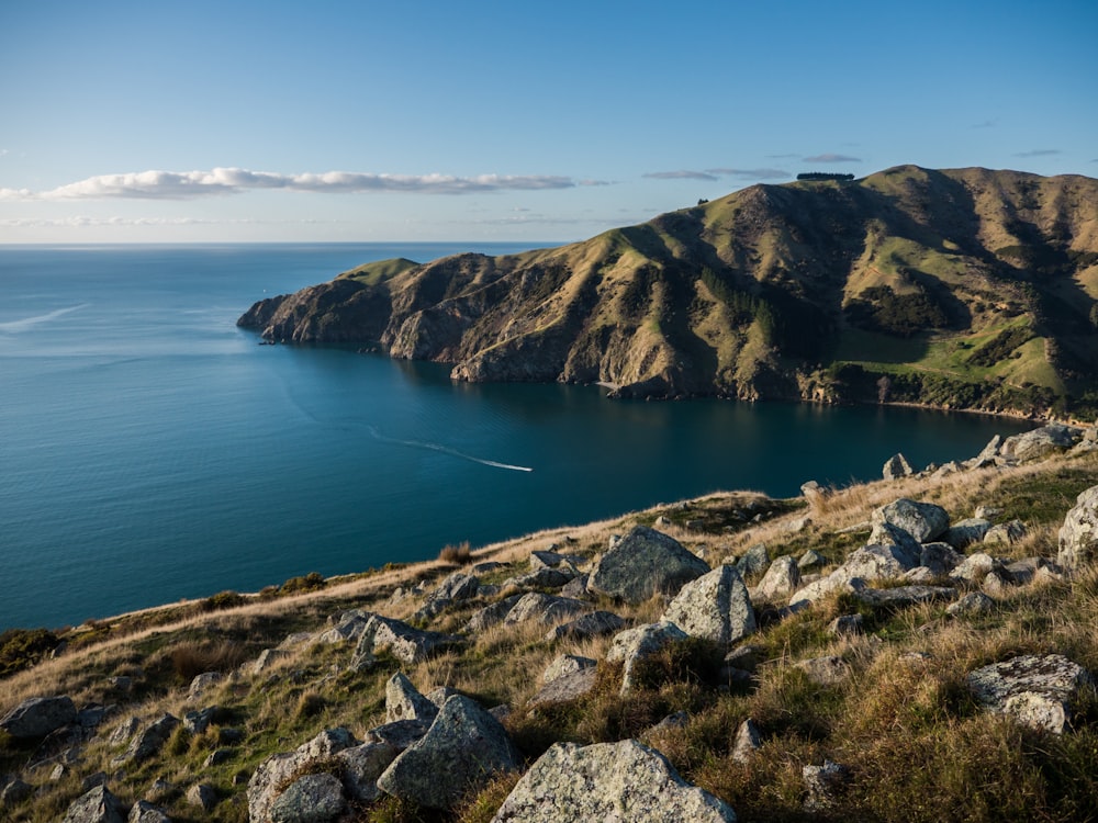 green and brown mountain beside blue sea under blue sky during daytime