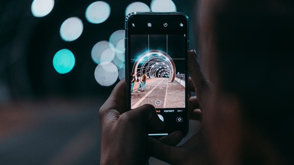 person holding iphone taking photo of white and black balloons